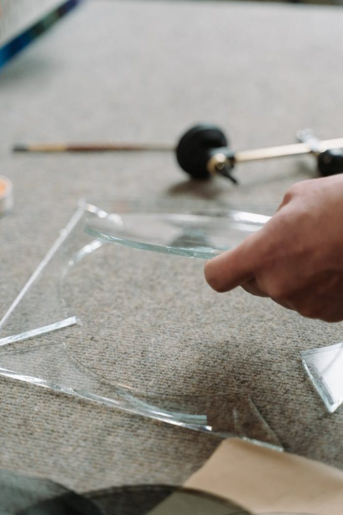 Focused shot of a craftsman cutting glass with precision in an industrial workshop.